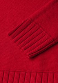 Maglione rosso a maglia con polsini e orlo a costine e texture liscia. Il tessuto appare morbido e presenta un motivo uniforme in tutto il capo.