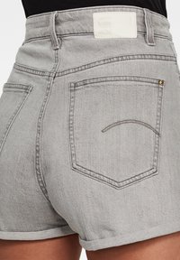 Harmaat farkkishortsit korkealla vyötäröllä, käänteet lahkeissa, takataskut ja huomaamattomat ompeluviivat. Valkoinen etiketti vyötärönauhan kohdalla.