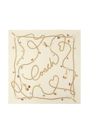 Écharpe crème ornée de chaînes dorées formant le mot "Coach" et des cœurs, décorée de petits charms tels que des cerises, des sacs et des dés.