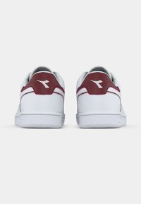 Λευκά αθλητικά παπούτσια με μαρουν λεπτομέρειες, κατασκευασμένα από λείο υλικό, με στρογγυλεμένη φτέρνα και υφή στη λαστιχένια σόλα. Λογότυπο κοντά στη φτέρνα.
