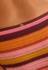 Gestricktes trägerloses Oberteil mit horizontalen Streifen in verschiedenen Pink-, Mahagoni-, Orange- und Gelbtönen, verziert mit einem kleinen goldenen Logo-Akzent.