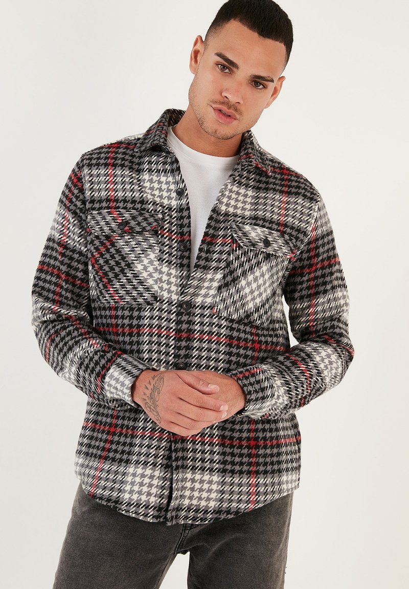Cămășă în carouri gri cu accente roșii, design cu nasturi, două buzunare pe piept și mâneci lungi. Fabricată dintr-un material texturat.