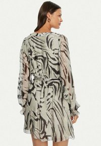 Abito a maniche corte, con motivo in tessuto trasparente. Presenta un design astratto nei toni del grigio e del marrone, cinonato in vita con una cintura.
