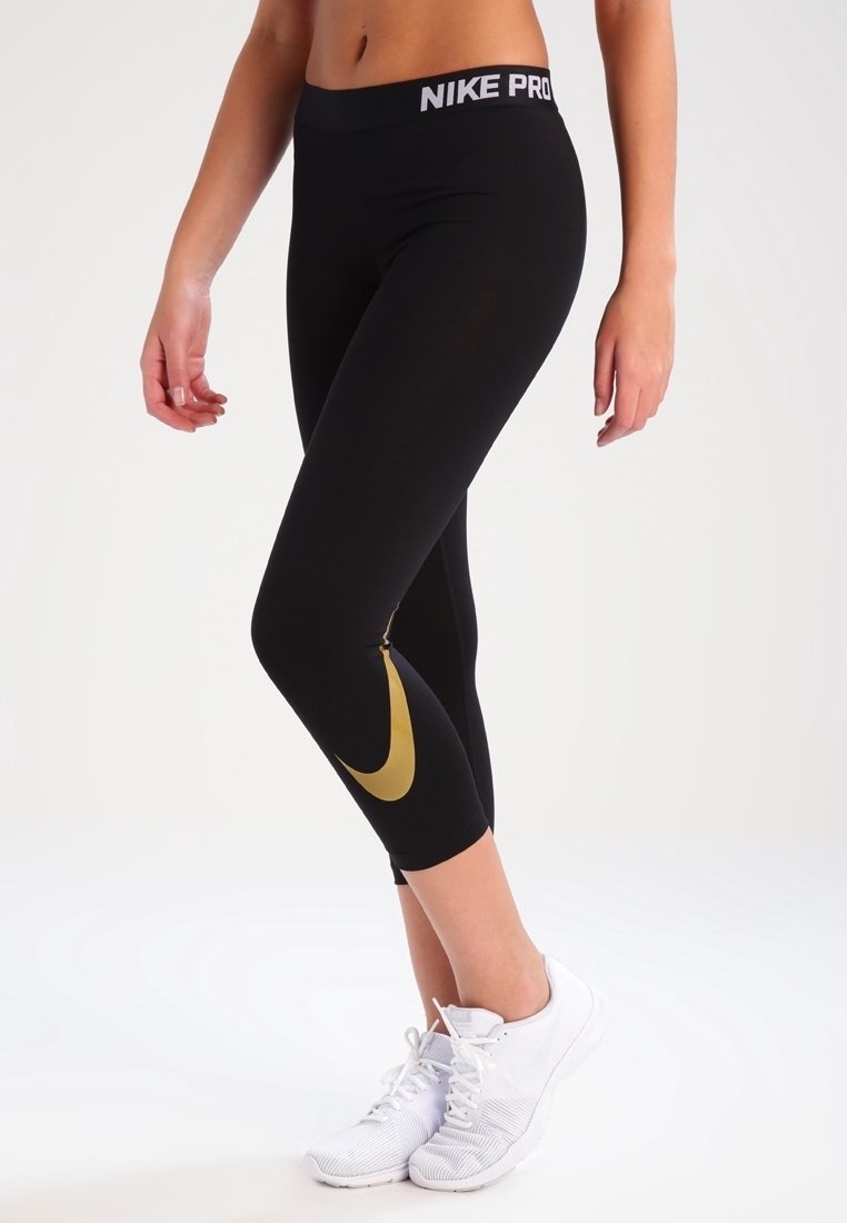 Czarne legginsy Nike Pro z złotym logo, z wysokim stanem i dopasowanym, elastycznym materiałem.