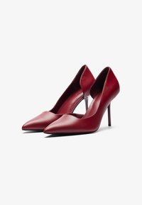 Punttit punttiaskelmat, valmistettu punaisesta nahasta, joissa on terävä kärki ja avonaiset reunat, sekä tyylikäs siluetti ja hoikka stilettokorko.