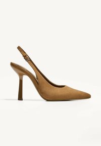 Tan suede slingback-korkokengät, joissa on terävä kärki ja kirkas kapeneva korko. Varustettu säädettävällä nilkkahihnalla mukavuutta ja tukea varten.