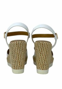 Sandali platform bianchi con tacco a zeppa in paglia intrecciata e cinturino alla caviglia. Materiale liscio con soletta color tabacco e dettaglio della fibbia in tonalità oro.