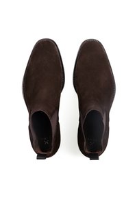 Bottines en daim marron avec des panneaux élastiques sur les côtés et des languettes de tirage. Texture lisse, bout arrondi et design minimaliste.