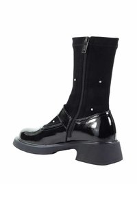 Czarne kozakowe buty za kolano z błyszczącym lakierowanym noskiem i obcasem, materiałową cholewką, bocznym zamkiem błyskawicznym oraz dekoracyjnymi srebrnymi ćwiekami.