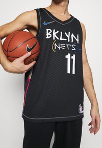 Black basketball jersey with herringbone texture, features "BKLYN (NETS)" in white and colorful accents, with number 11 on the front.