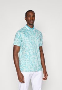 Camisa polo azul clara com um padrão em forma de onda, placket de três botões e colarinho listrado em contraste. Textura suave e mangas curtas.