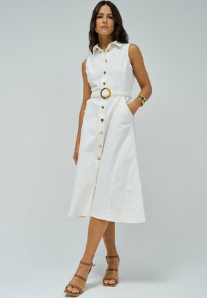Bela brezrokavna jeans obleka z gumbi, pasirana v pasu z okroglo sponko, z bočnimi žepi in razširjenim robom.
