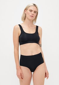 Svart sømløs bralette med brede stropper, firkantet utringning og matchende høy midje-bunn. Glatt tekstur, minimalisk design.