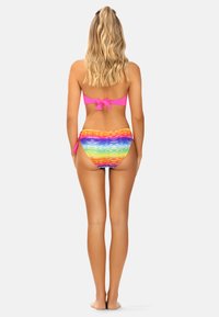 Zestaw bikini składający się z różowego topu bandeau z wiązaniem z tyłu oraz wielokolorowych majtek wiązanych po bokach z abstrakcyjnym wzorem fal.