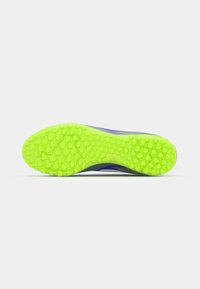 Football shoe with a textured neon green rubber sole featuring honeycomb patterns, designed for traction on turf surfaces.