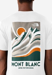 Camiseta blanca con un diseño gráfico del Mont Blanc, con un sol naranja, montañas verdes y patrones ondulados en beige y naranja.
