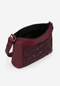Bolso bandolera de cuero burdeos con un panel texturizado y brillante. Cuenta con un cierre de cremallera y correa ajustable. Superficie suave, forma estructurada.