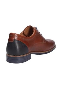 Chaussure en cuir marron à finition lisse, avec une accent noir texturé au niveau du talon et une semelle en caoutchouc foncé. Lacets présents à l'avant.