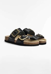 Zwarte leren sandalen met twee brede banden, gouden gespen, een kurken voetbed en een zwarte rubberen zool. Glad oppervlak met een minimalistisch ontwerp.