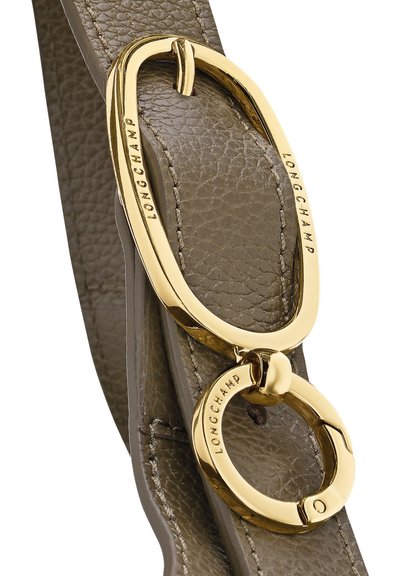 Gold-toned Longchamp branded oval and circular metal rings attached to textured taupe leather strap with visible stitching.