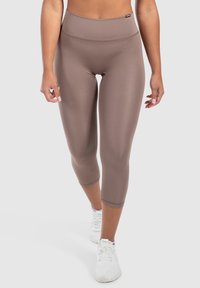 Leggings capri marroni a vita alta con una texture liscia e elastica. Presentano un design semplice e un'etichetta con il marchio in vita.