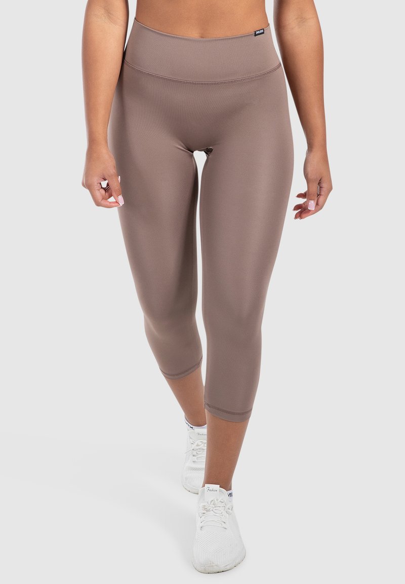 Leggings capri marroni a vita alta con una texture liscia e elastica. Presentano un design semplice e un'etichetta con il marchio in vita.