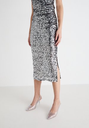Robe midi à sequins avec une silhouette ajustée ; couleurs argent et noir, fente sur le côté, texture brillante. Assortie à des talons aiguilles argentés.