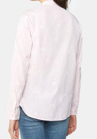 Ljusrosa långärmad skjorta med vita broderade palmer, en knäppkrage och rundad nederkant. Tillverkad av bomullsblandning.