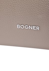 Beżowy skórzany portfel o teksturowanym wykończeniu, z dobrze widocznym srebrnym logo "BOGNER". Czysty, minimalistyczny design.