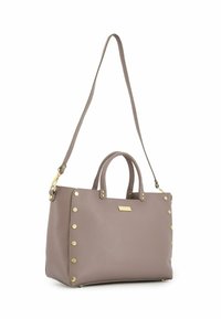 Grijze leren tote bag met gouden studs langs de zijkanten, dubbele handvatten bovenaan en een afneembare schouderriem. Gladde textuur, rechthoekige vorm.