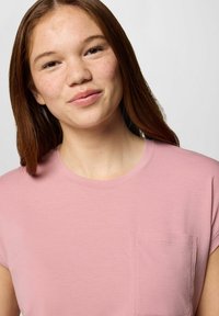 T-shirt rosa a maniche corte realizzata in tessuto morbido, con colletto tondo e taschino sul lato sinistro del petto. Tessuto liscio, design semplice.