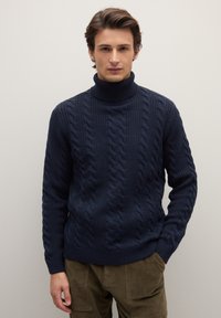 Marineblauer Rollkragenpullover mit Zopfmuster, der dicke Zöpfe und gerippte Details aufweist. Hergestellt aus strukturiertem Strickstoff, mit figurbetonter Silhouette.