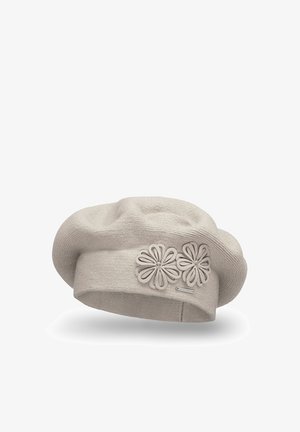 Hellbeige Beret aus Strickmaterial, versehen mit einem Band mit zwei Blumenapplikationen und einem kleinen Markenschild. Weiche Textur und runde Form.