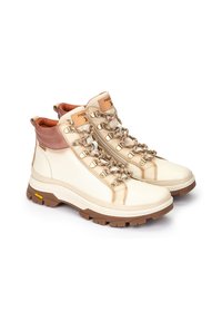 Botas de senderismo en tonos beige y marrón con un diseño de caña alta, ojales de metal, cordones texturizados y una suela de goma resistente. Cuenta con un suave forro interior.