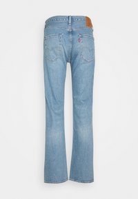 Vaqueros acampanados de color azul claro con un diseño clásico de cinco bolsillos, que incluyen una parche trasera de cuero marrón y una sutil textura desteñida.