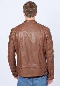 Braune Lederjacke mit taillierter Passform, gerippten Schulterakzenten und glatter Textur. Verfügt über seitliche Anpassungsbuckle und genähten Details.