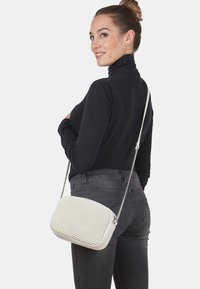 Borsa a tracolla bianca con fronte strutturato, lati lisci e tracolla a catena. Presenta una forma rettangolare e un sottile motivo intrecciato.