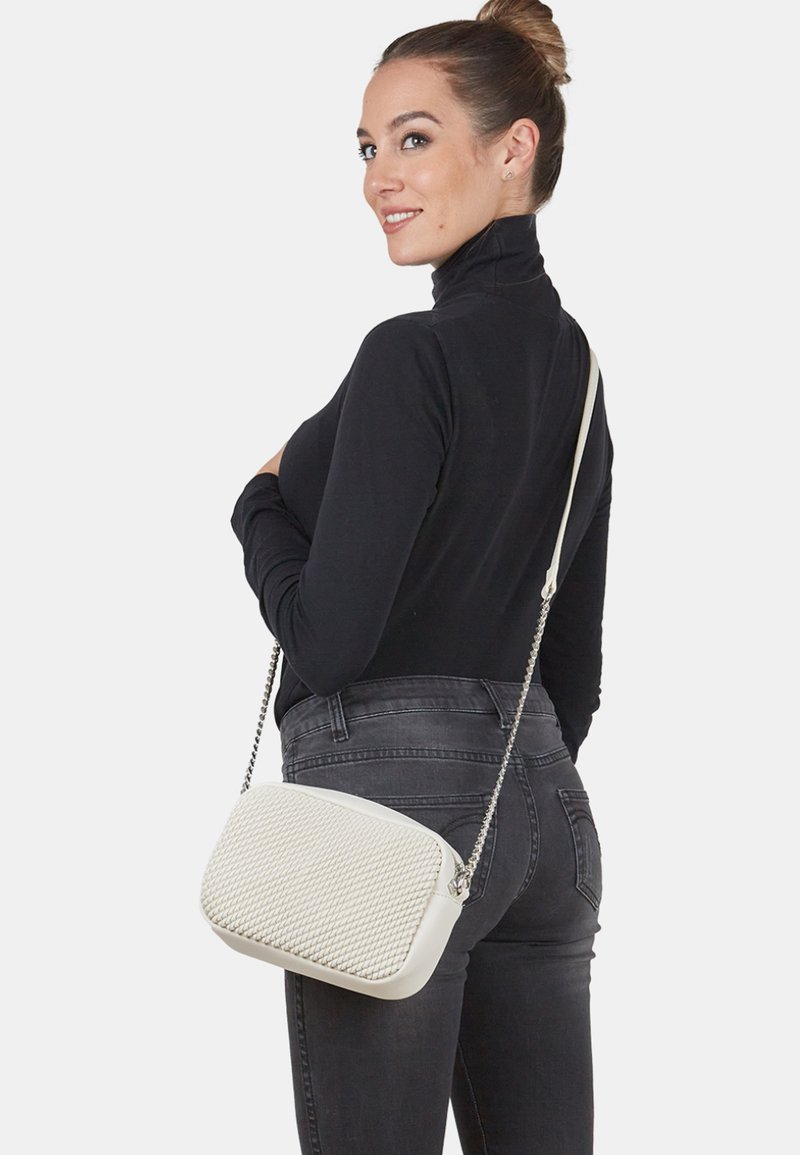 Borsa a tracolla bianca con fronte strutturato, lati lisci e tracolla a catena. Presenta una forma rettangolare e un sottile motivo intrecciato.