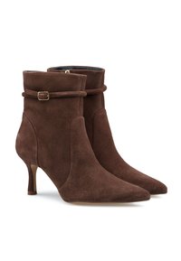 Stivali alla caviglia in suede marrone con punta affusolata, tacco sottile e cinturino avvolgente con una fibbia in tono oro. Texture liscia e forma aderente.