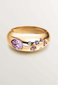 Anillo de oro con múltiples piedras preciosas, incluyendo piedras moradas y transparentes en corte pera y redondo, montadas en una banda suave y redondeada.