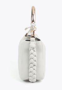 Vit läderhandväska med ett flätat handtag och en cirkulär accent i guldtonad metall. Slät yta, kompakt form, minimalistisk design.