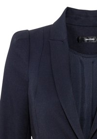 Námorně modrý blazer se strukturovanými rameny, klopovým límcem a hladkým tkaninovým povrchem. Má jednoduchý, elegantní design bez vzorů nebo akcentů.