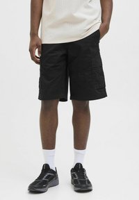 Black cargo shorts with multiple pockets, knee-length cut, and a smooth cotton texture. Paired with black athletic shoes and white socks.