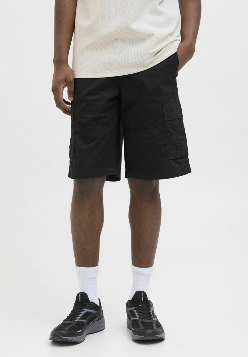 Black cargo shorts with multiple pockets, knee-length cut, and a smooth cotton texture. Paired with black athletic shoes and white socks.