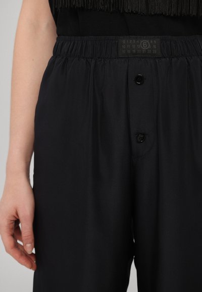Black, elastic-waist pants with two black buttons at the front, smooth texture, and gathered fabric along the waist.
