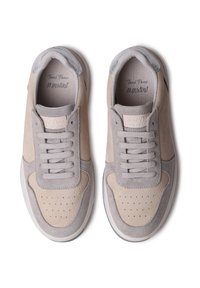 Bežid ja hallid tenis kingad, mis on valmistatud sametist ja tekstureeritud nahast. Neil on augustatud varvaste kasti, lamedad paelad ja pehme krae.