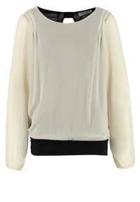 Blouse crème à manches longues avec ceinture élastique noire et détail dos en forme d’œil-de-bœuf, en tissu léger.