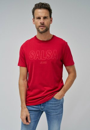 T-shirt en coton rouge avec un col rond et des manches courtes. "SALSA JEANS" imprimé en lettres majuscules sur le devant. Coupe décontractée et légère.