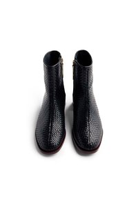 Botas de tobillo de cuero trenzado negro con punta afilada, que cuentan con un cierre de cremallera en el costado y un forro interior suave.