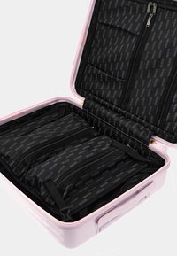 Valigia rigida rosa con interno aperto caratterizzato da rivestimento in tessuto nero e numerosi scomparti con cerniera per l'organizzazione.
